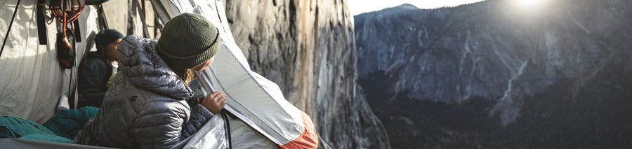 Man facing sunset using portaledge to hang off cliff face