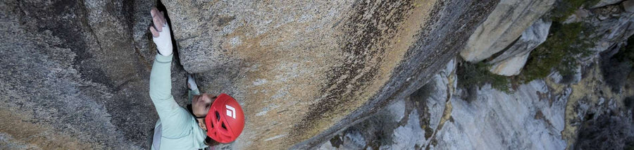 Woman in climbing gloves scaling a sheer rock wall outdoors