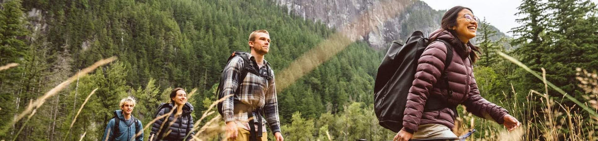 People scaling rock formation outdoors wearing climbing bags