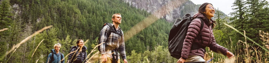 People scaling rock formation outdoors wearing climbing bags