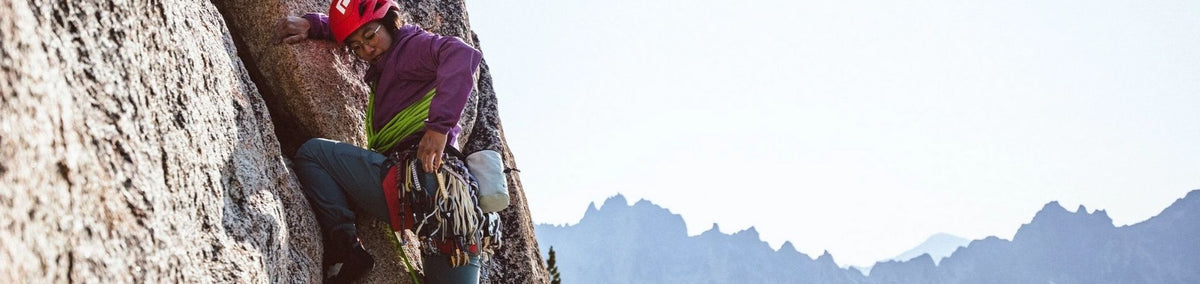 Woman in harness and an array of carabiners climbing a mountain side