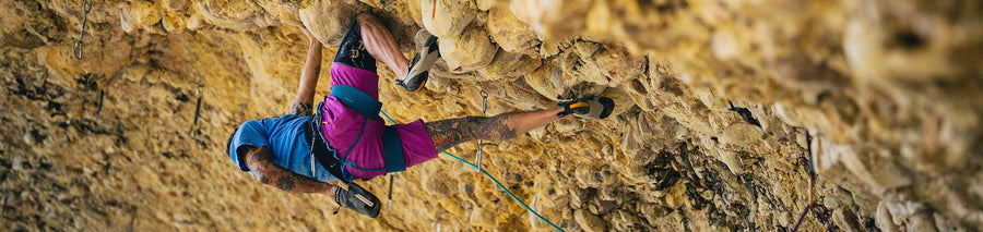 Man climbing up sheer rock wall outdoors