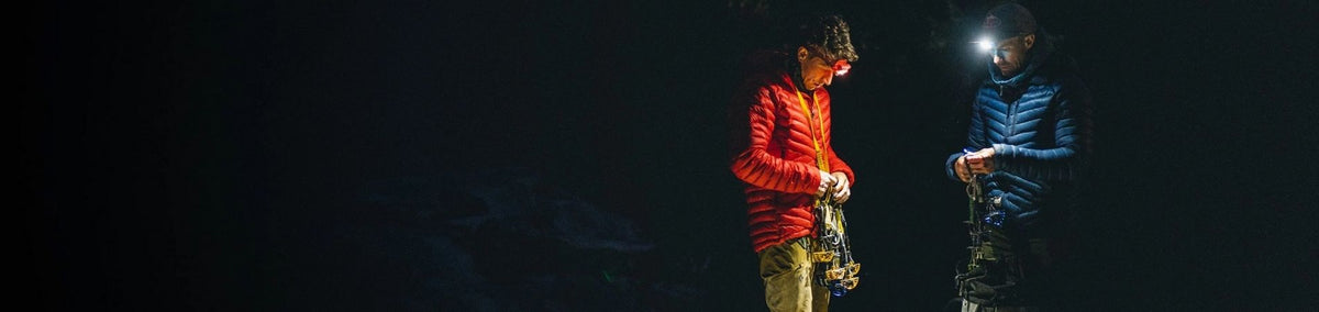 Two people inspecting their equipment in the dark assisted by headlamps