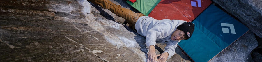 Man in white hoodie climbs cliff face