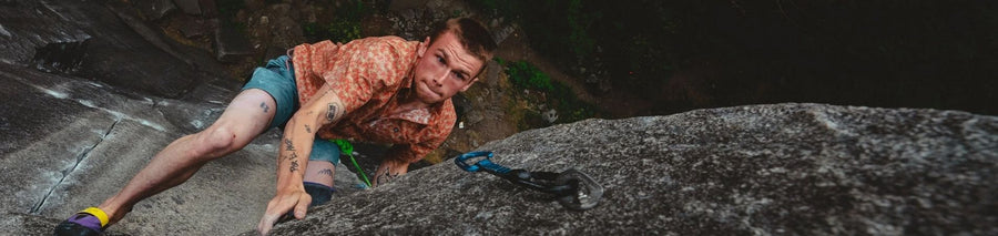 Man in patterned button up shirt climbing rock