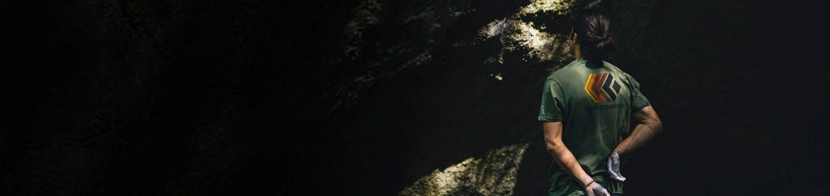 Back of man in green tee shirt facing rock wall