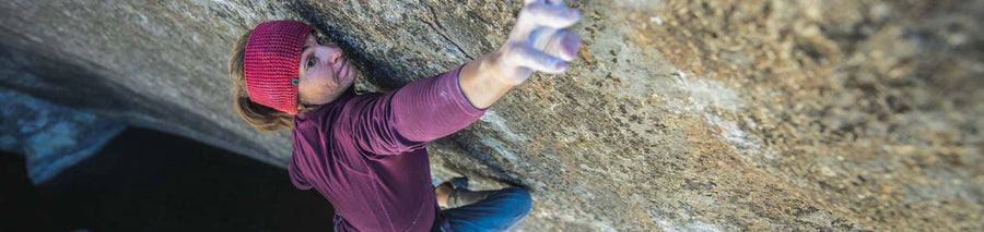 Woman in a red fleece jacket climbing a rock wall