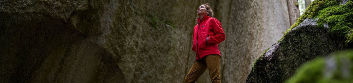 Woman in bright red jacket smiling up at a canyon rock wall