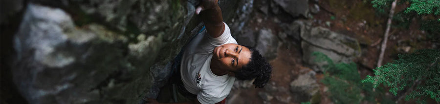 Woman with white tee shirt outside climbing a rock wall
