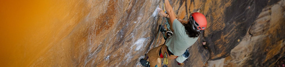 Woman adorned in climbing gear as she climbs a sheer rock wall