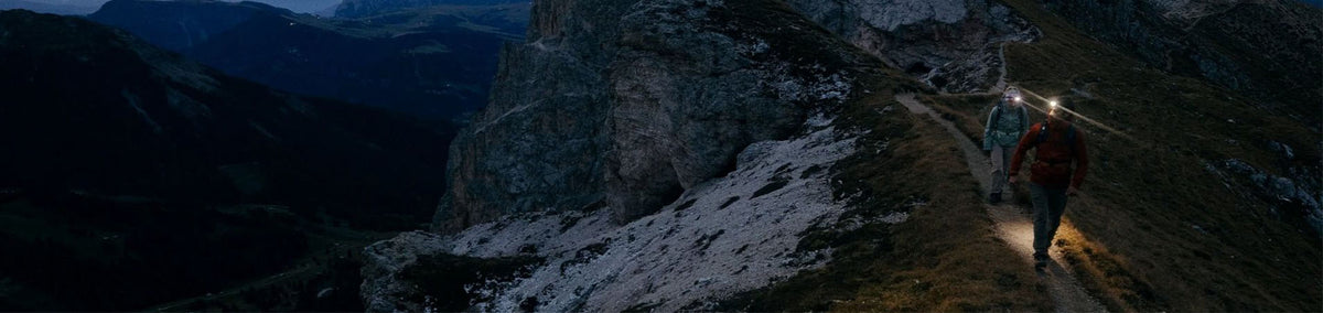 Person walking outdoors at night with headlamp providing light