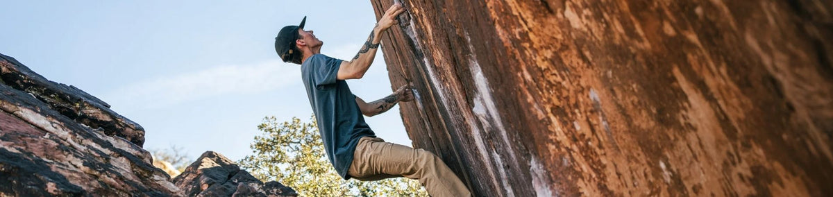 Man in blue shirt free climbing rock wall